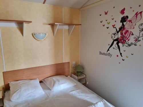 La BétaudièreMobil home sur camping 4 étoiles CAP SOLEIL St Denis d'Oléron的卧室配有一张带蝴蝶贴纸的床铺。