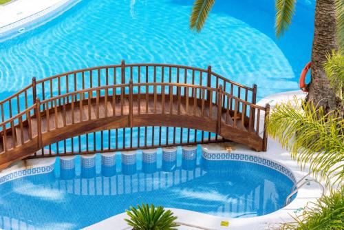 坎布里尔斯Mònica Hotel的游泳池上方设有木桥