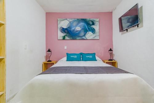 墨西哥城Ayenda Los Colorines de Coyoacán的卧室配有带蓝色枕头的大型白色床