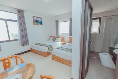 莲三Luxury hotel Phú Yên的酒店客房设有两张床和一张桌子。