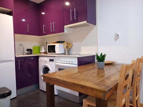 特鲁埃尔Apartamento Alcázar parking incluido VU-TERUEL-18-035的厨房配有紫色橱柜和木桌