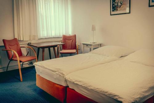 普特布斯Inselgaestehaus-Erna的酒店客房配有一张床、两把椅子和一张桌子
