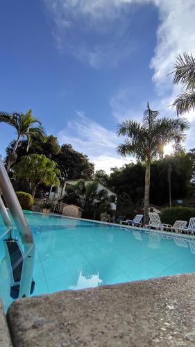 佩尼多Pousada Chez Nous的一个带椅子和棕榈树的大型蓝色游泳池