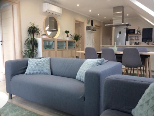 凯斯特海伊Galéria Apartmanház的一间带蓝色沙发的客厅和一间用餐室