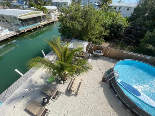 马拉松Luna Bay Breeze的游泳池旁设有椅子和棕榈树,旁边是河流