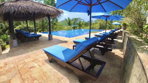 高尔尼娅伽玛屋酒店的游泳池旁的一排躺椅和遮阳伞