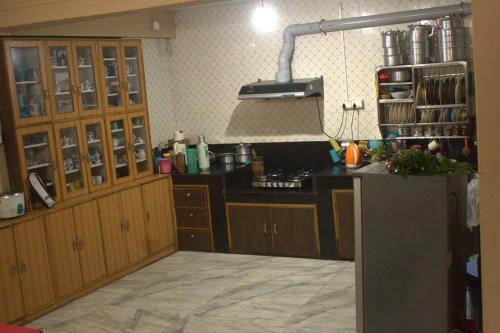 甘托克BOJO House的厨房配有木制橱柜和黑色台面
