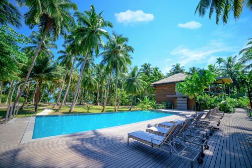 哈夫洛克岛Tilar Siro Andamans - CGH Earth的一个带躺椅的度假村游泳池,并种植了棕榈树