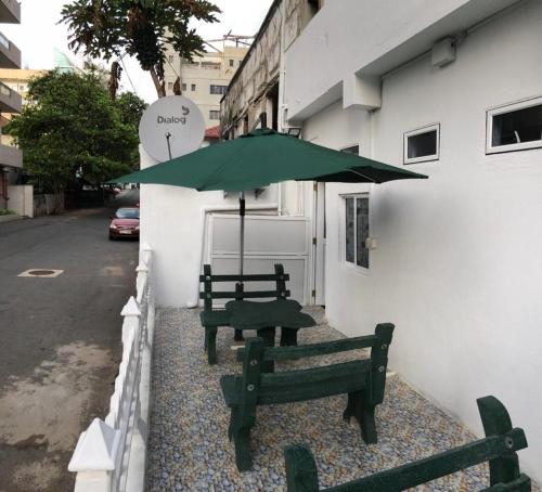 科伦坡WISH RESIDENCE SEASIDE Colombo3的两个长椅,坐在带雨伞的建筑旁边