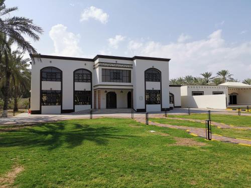索哈尔بيت العز السياحي Al-Ezz Tourist House的一座大型白色建筑,设有大窗户和庭院