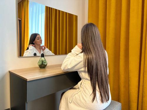 波利亚纳Arena Apart - Hotel的坐在镜子前的桌子上的女人