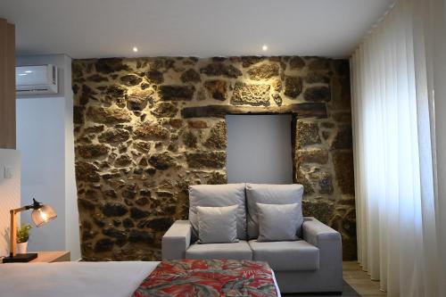 拉梅戈O Visconde - Alojamento local的一间卧室设有石墙、沙发和椅子