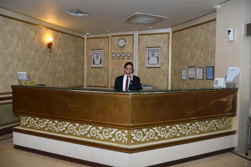 科威特Continental Suite farwaniya的坐在前台里穿着西装的人