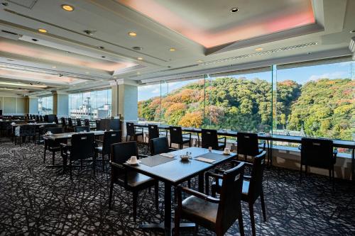 松山ANA Crowne Plaza Matsuyama, an IHG Hotel的餐厅设有桌椅和大窗户。