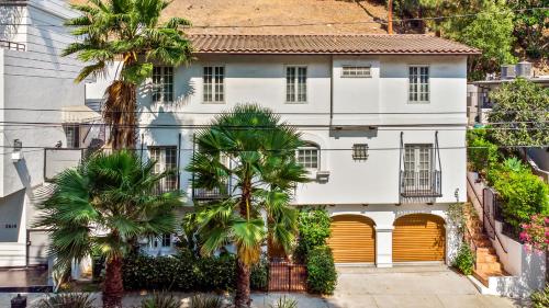 洛杉矶Hollywood Hills Homestay的白色的房子,有黄色的门和棕榈树