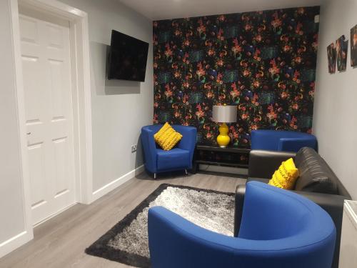 吉夫诺克Saphire Glasgow Apartments的客厅配有蓝色椅子和壁画