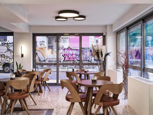 雅典NLH KERAMEIKOS - Neighborhood Lifestyle Hotels的餐厅设有桌椅和窗户。