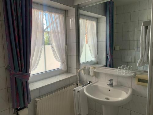 赫茨拉克弗洛拉酒店的一间带水槽和镜子的浴室以及窗户。