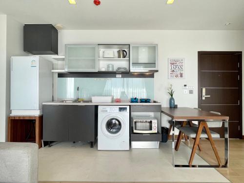 清迈THE ASTRA CONDO 2 BEDROOMS BY PING的厨房配有洗衣机和桌子