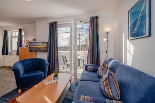 黑灵斯多夫Ferienwohnung Kon-Tiki, Villa Regina Maris Bansin的客厅配有蓝色的沙发和桌子