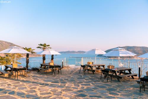 巨济Hotel SANG SANG & Private SANG SANG POOL VILLA的海滩上的一组桌子和遮阳伞