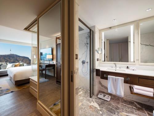 首尔首尔大使 - 铂尔曼酒店的带淋浴和盥洗盆的浴室以及1张床。