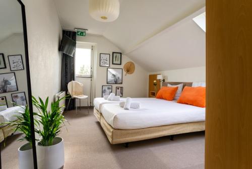Loenen卢讷尔马克酒店餐厅的一间卧室配有两张带橙色枕头的床