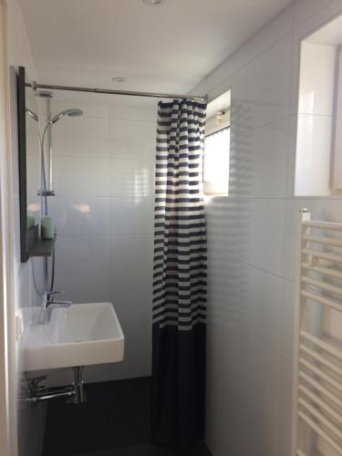 海边的艾格蒙特Zomerhuis Zuid 1的浴室设有黑色和白色的浴帘和水槽