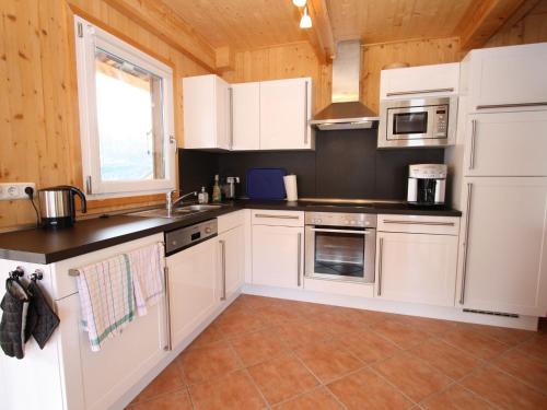 上陶恩Wooden chalet in Hohentauern Styria with sauna的厨房配有白色橱柜和台面