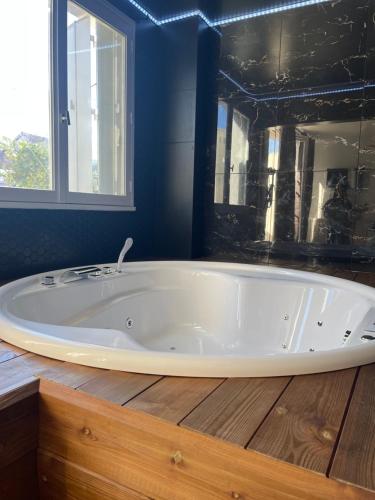 勒布朗-梅尼尔Seasides Paris - Suite Monroe的浴室设有蓝色墙壁和大型白色浴缸。
