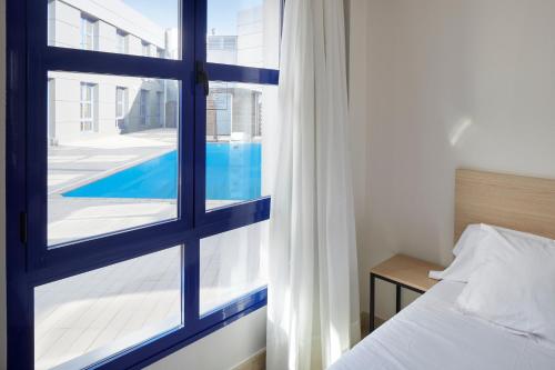 洛格罗尼奥Iraipe Logroño Hotel的一间卧室,透过窗户可欣赏到游泳池的景色