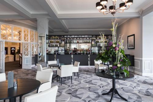 圣奥斯特尔The Carlyon Bay Hotel and Spa的一间带桌椅的餐厅和一间酒吧