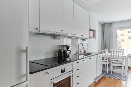 KnivstaContinental Apartment Hotel Knivsta的厨房配有白色橱柜和黑色台面