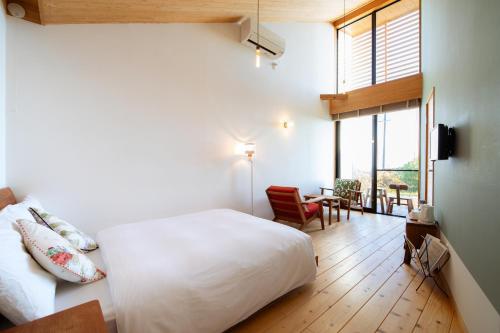 屋久岛Ananda Chillage Yakushima的一间卧室配有一张床、一张书桌和一个窗户。