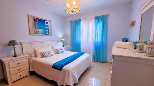 塞博河畔卡莱塔La Graciosa Mykonos Beach, Junior Suite的卧室配有白色的床和蓝色窗帘