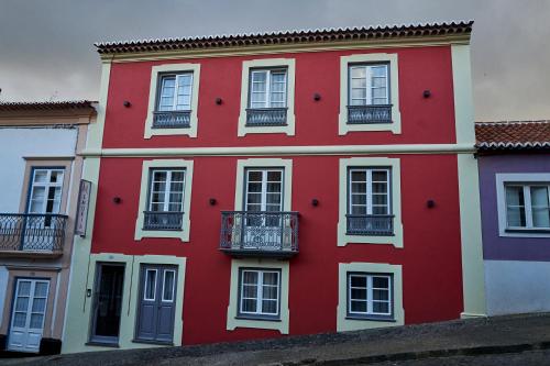 英雄港Memória Boutique Hostel的红色的建筑,设有白色的窗户和阳台