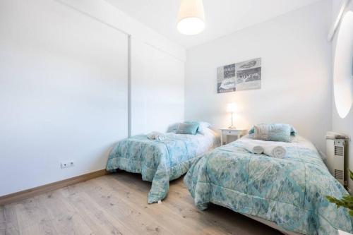 阿尔布费拉Casa das Cores的配有白色墙壁和木地板的客房内的两张床