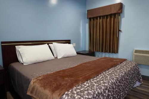 洛杉矶24 Hours Motel的卧室配有带白色枕头的大床