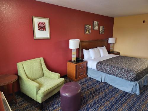 安吉利斯港Olympic Inn & Suites Port Angeles的配有一张床和一把椅子的酒店客房