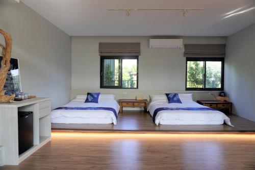 公馆藴慢築 茶花藝主題民宿 Yun Man Zhu Homestay的一间卧室设有两张床和两个窗户。