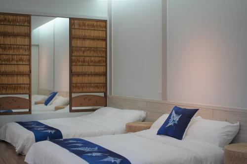 公馆藴慢築 茶花藝主題民宿 Yun Man Zhu Homestay的带三张床和镜子的客房