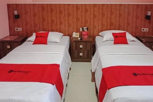 索龙RedDoorz @ Sorong City Center的两张位于酒店客房的床铺,配有红色枕头