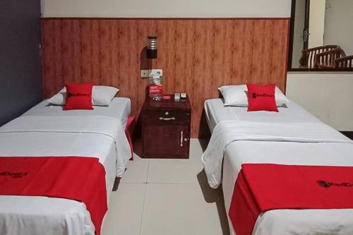 索龙RedDoorz @ Sorong City Center的两张位于酒店客房的床铺,配有红色枕头