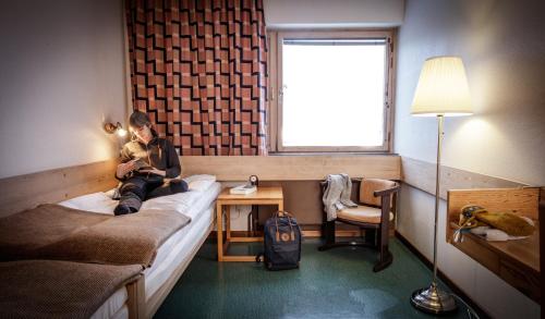 EdsåsdalenKöja Fjällhotell的坐在房间里床边的女人