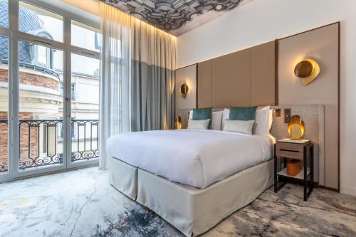 巴黎InterContinental Paris Champs Elysées Etoile, an IHG Hotel的一间卧室设有一张大床和一个大窗户