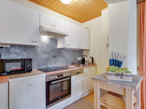 费斯Lively flat near a ski resort in Fiss的厨房配有白色橱柜和一张带一碗水果的桌子