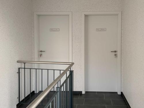 迪楚姆Ferienwohnungen Molkerei Ditzum 45242的两扇白色门,位于一栋设有楼梯的建筑内