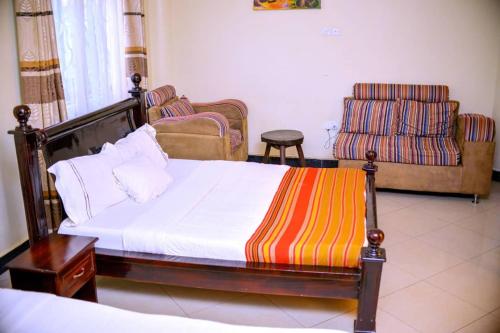 坎帕拉Acactus Hotel的一间卧室配有一张床、一张沙发和一把椅子