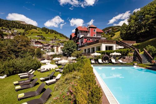 圣克里斯蒂娜玛西亚科尼精品时尚酒店的一座带游泳池和椅子的度假村和一座建筑