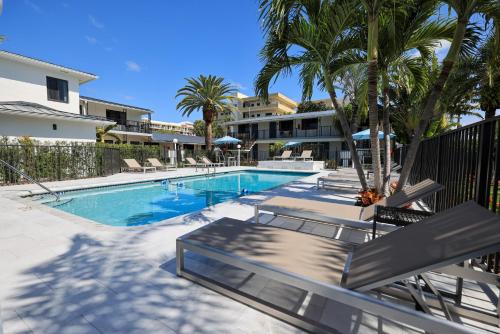 迪尔菲尔德海滩热带岛海滩度假村汽车旅馆的一座棕榈树游泳池,位于酒店大楼旁